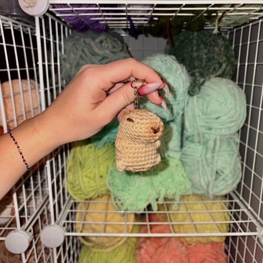 Capybara crochet keychain being held in the left hand, 4 inches in size